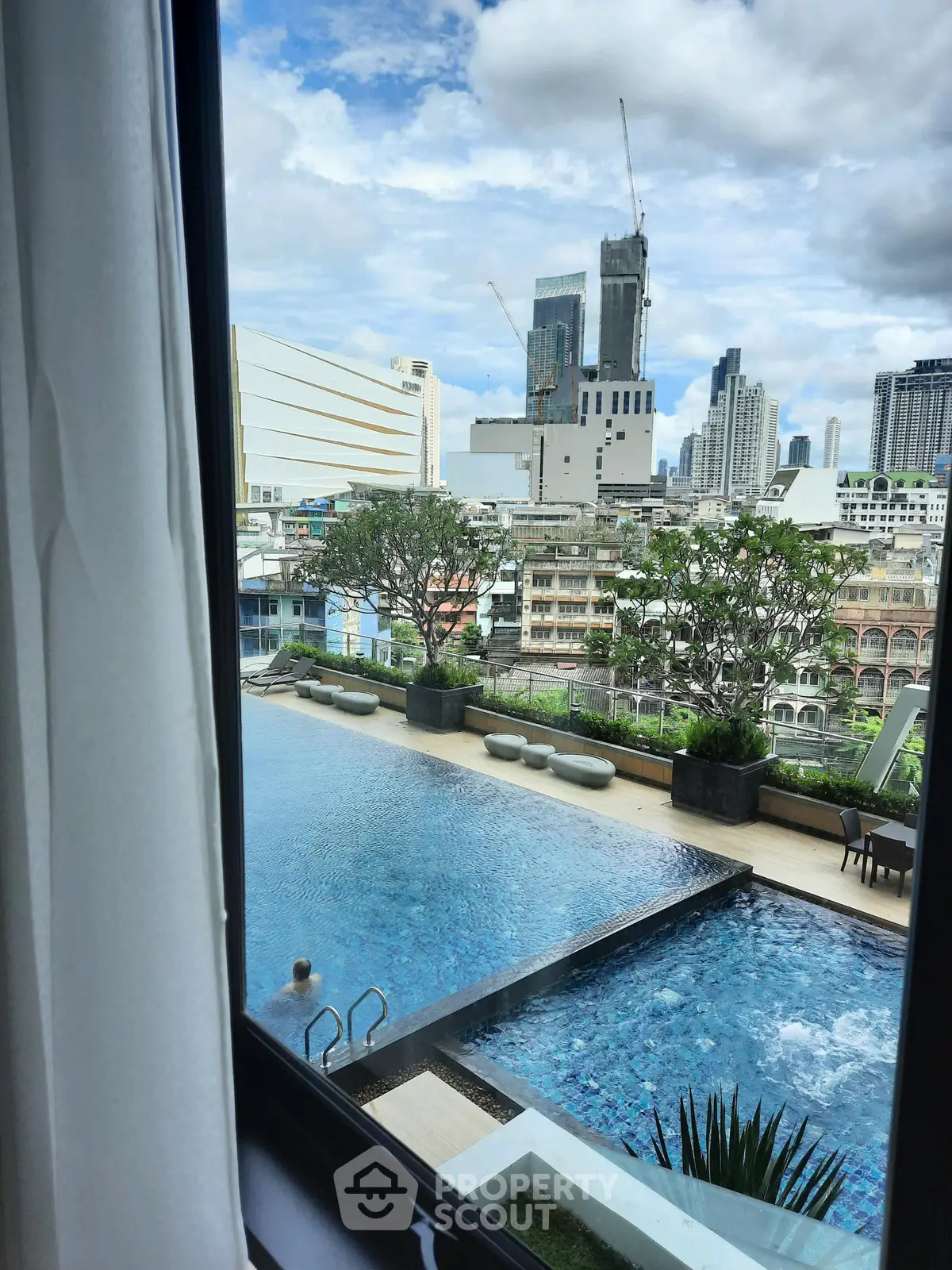 Luxurious city view from window overlooking modern pool and skyline