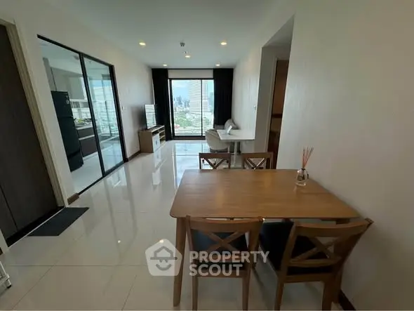 Modern apartment interior with dining area and city view, featuring sleek design and natural light.