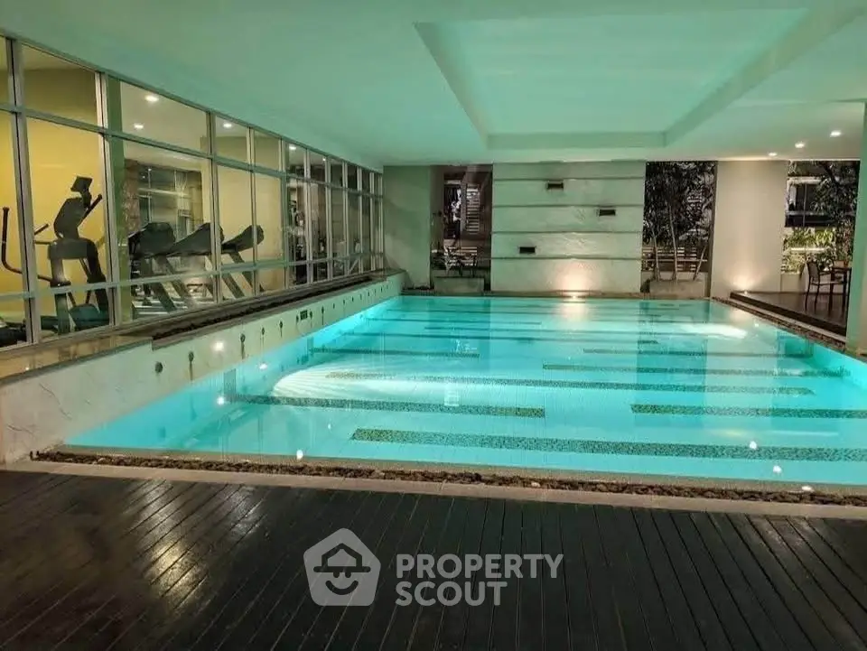 Luxurious indoor swimming pool with modern design and ambient lighting in upscale residential building.