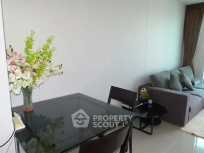 Modern living room with glass dining table and cozy sofa, perfect for relaxation and entertaining.
