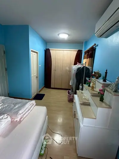 Cozy bedroom with blue walls, wooden flooring, and ample storage space.