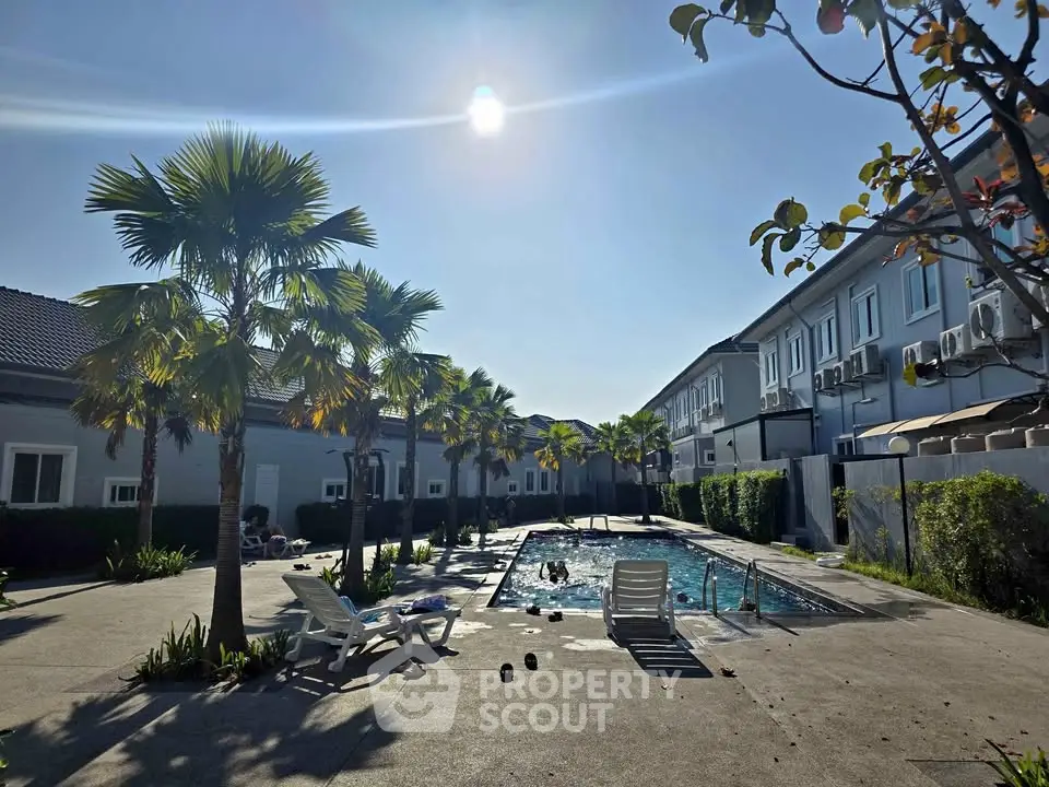 Stunning residential pool area with palm trees and sunlit ambiance