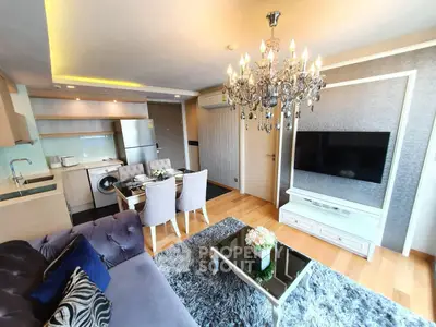Luxurious living room with elegant chandelier and modern kitchen in open layout apartment