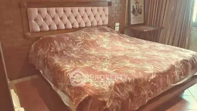 Cozy bedroom with elegant tufted headboard and floral bedspread, perfect for relaxation.