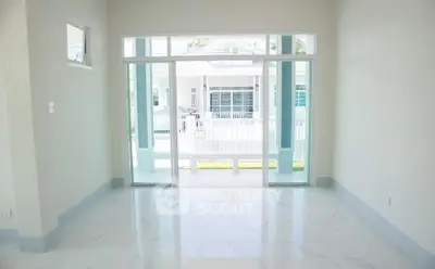 Bright empty room with large sliding glass doors and a view of a white house exterior.