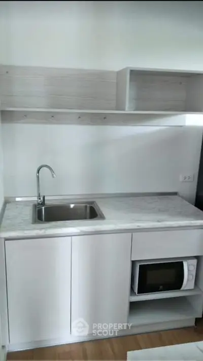 Modern compact kitchen with sleek cabinetry and built-in microwave, perfect for urban living.
