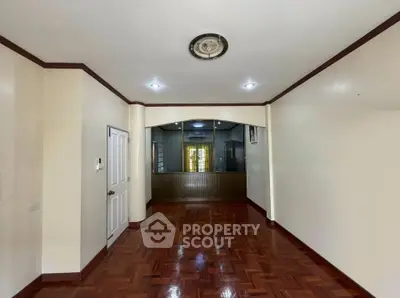 Spacious empty room with polished wooden floors and elegant ceiling light fixture.