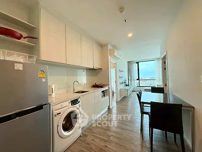 Modern open-layout kitchen and dining area with washing machine and scenic view.