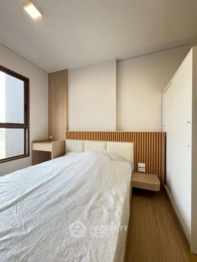 Modern bedroom with minimalist design and wooden accents, featuring a large window for natural light.