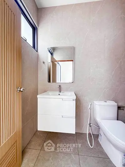 Modern bathroom with sleek fixtures and elegant tile design, featuring a stylish vanity and toilet.