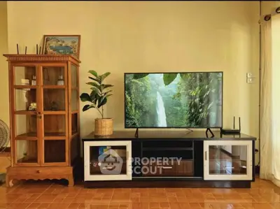 Charming living room with elegant wooden cabinet and modern TV setup, perfect for cozy family gatherings.