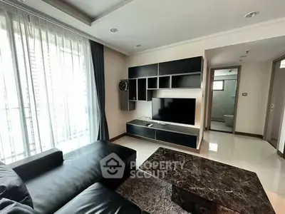 Modern living room with sleek black furniture and large TV, perfect for relaxation.