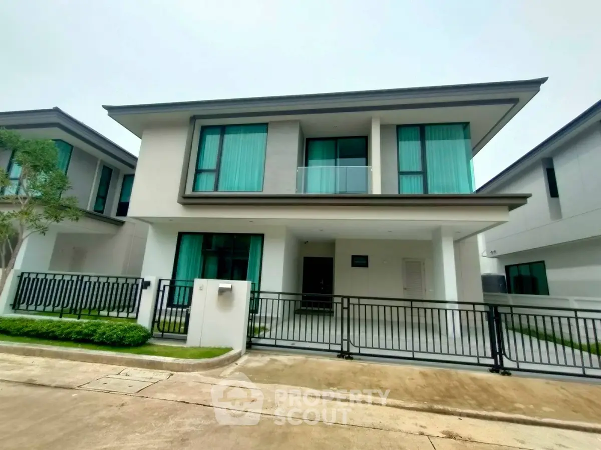 Modern two-story house with sleek design and large windows in a suburban neighborhood.