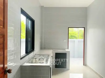 Modern kitchen with sleek design and outdoor access, featuring a large window and minimalist style.