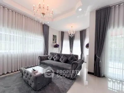 Luxurious living room with elegant gray sofa, plush rug, and chandeliers in a bright, airy space.