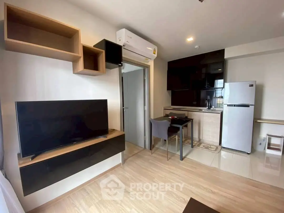 Modern living room with sleek kitchen, featuring stylish furniture and contemporary appliances.