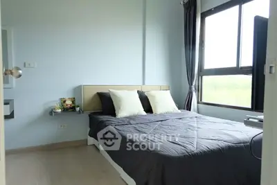Cozy bedroom with large window and modern decor in a serene setting.