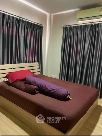 Cozy bedroom with modern decor and air conditioning, featuring elegant curtains and wooden flooring.