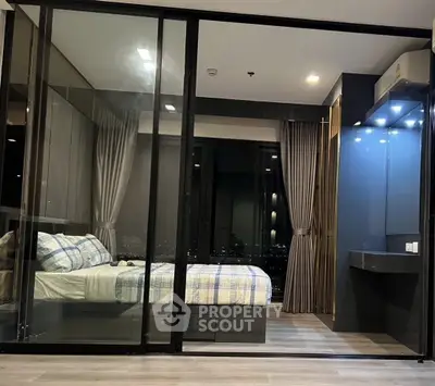 Modern bedroom with glass partition and city view, featuring stylish decor and ambient lighting.
