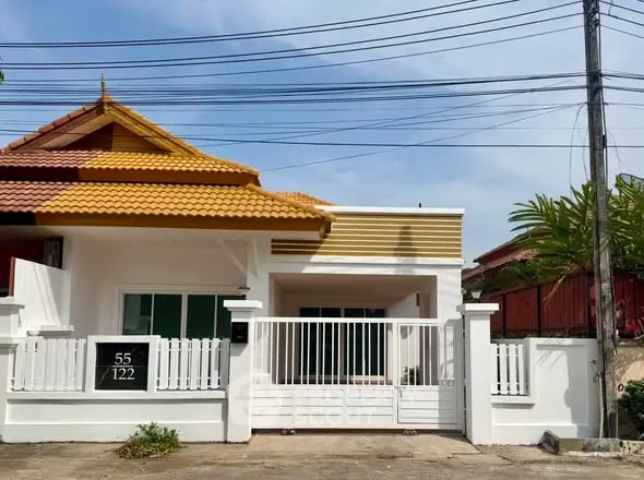 Charming single-story house with a unique roof design and gated entrance, perfect for family living.