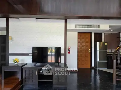 Spacious living room with modern TV setup and sleek kitchen area.