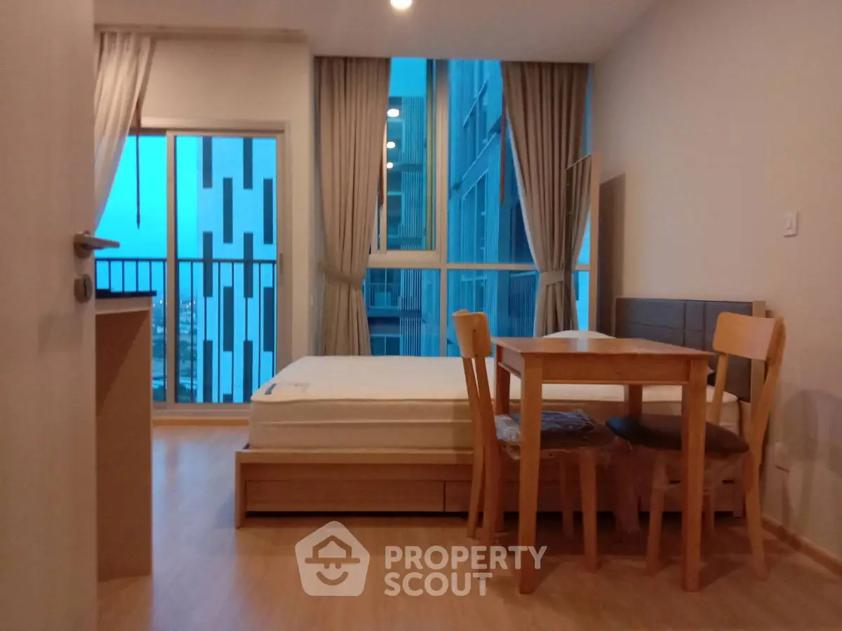Cozy studio apartment with modern furnishings and large windows offering city views.