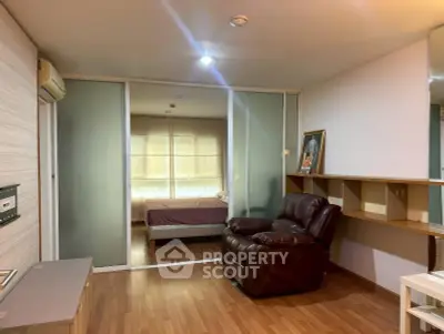 Spacious living room with leather armchair and sliding doors leading to a cozy bedroom.