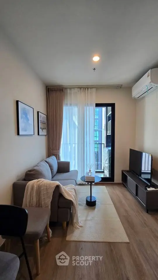 Modern living room with cozy sofa, TV, and balcony access in a stylish apartment.