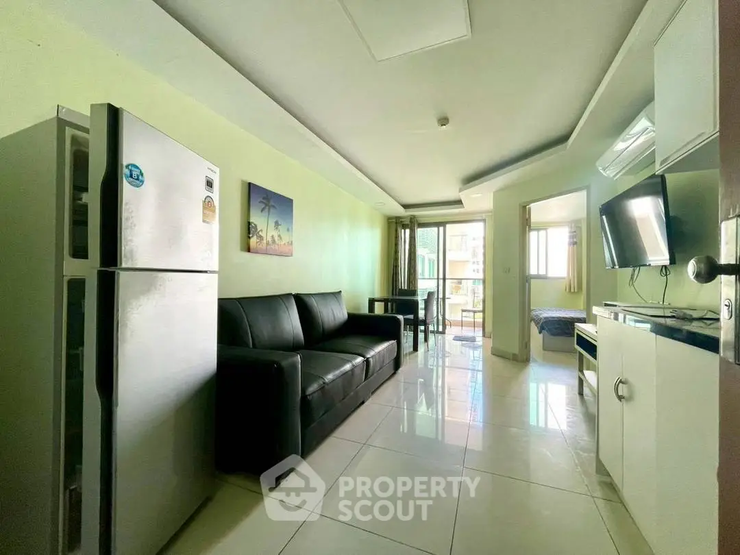 Modern apartment with sleek living room and kitchen, featuring a comfortable sofa and large refrigerator.