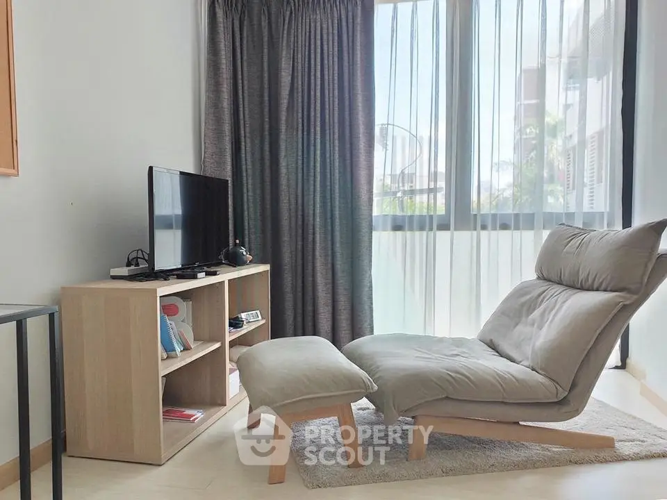 Cozy living room with modern lounge chair and TV setup, perfect for relaxation.