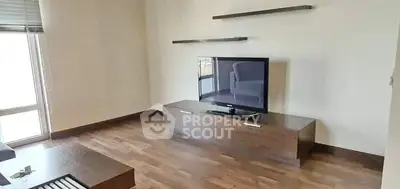 Modern living room with sleek wooden flooring and minimalist TV setup.