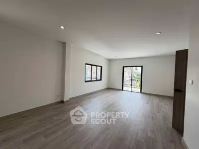Spacious empty room with large windows and wooden flooring, ideal for customization.