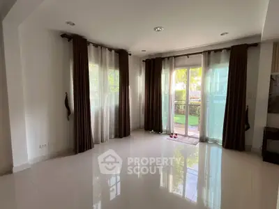Spacious living room with large windows and garden view, perfect for natural light lovers.