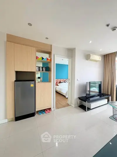 Modern living room with sleek design, featuring a TV, air conditioning, and a glimpse into a cozy bedroom.