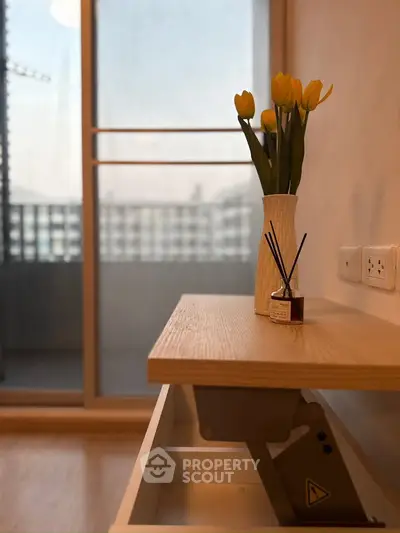 Modern apartment interior with stylish decor and balcony view, featuring a sleek wooden table and vibrant yellow tulips.