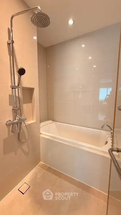 Modern bathroom with sleek bathtub and rainfall showerhead in a stylish real estate property.
