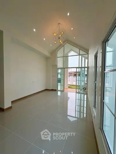Spacious modern living room with high ceilings and large windows, offering abundant natural light and elegant design.