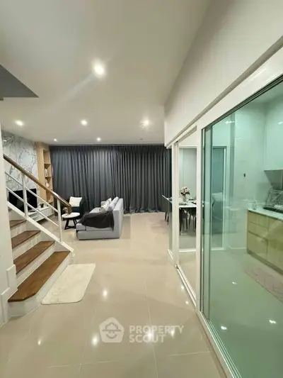 Spacious modern living room with elegant staircase and open dining area, perfect for family gatherings.
