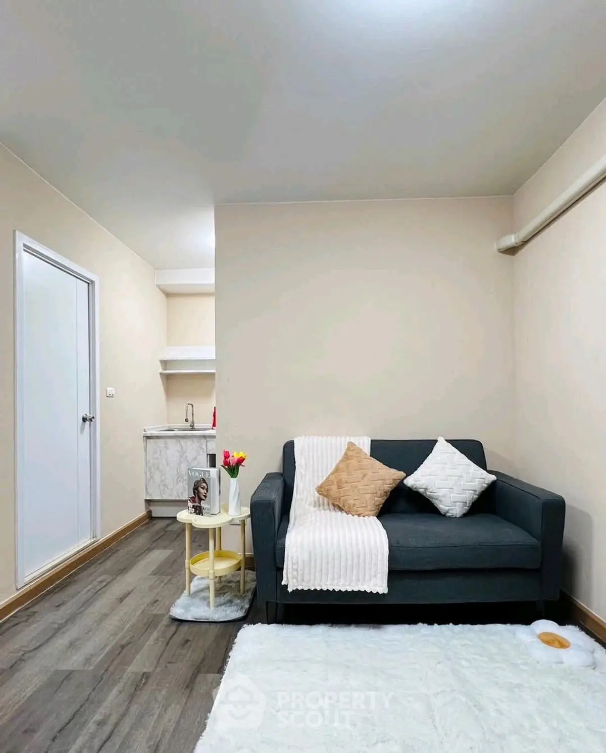 Cozy living room with modern sofa and small kitchenette, perfect for urban living.