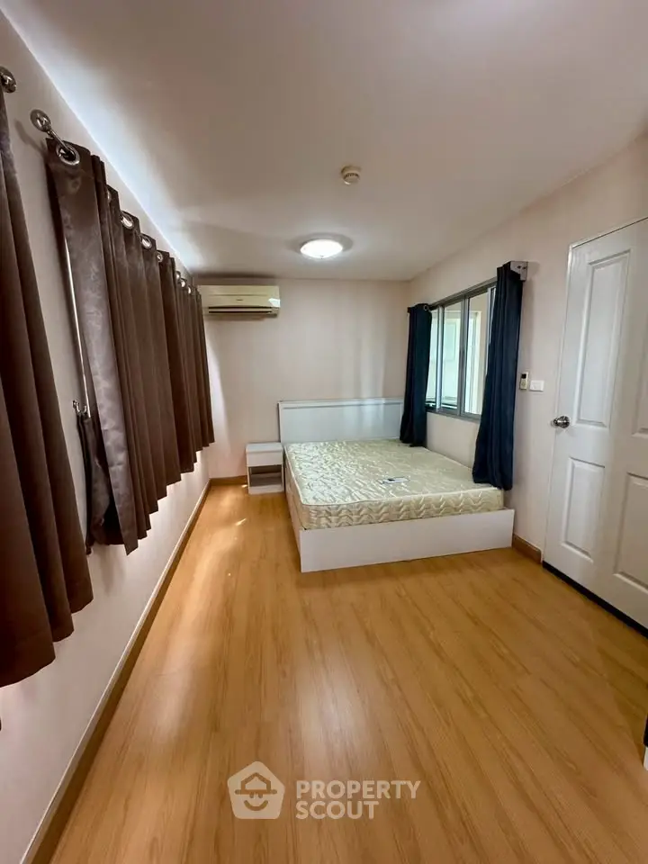 Spacious bedroom with wooden flooring and large windows for natural light
