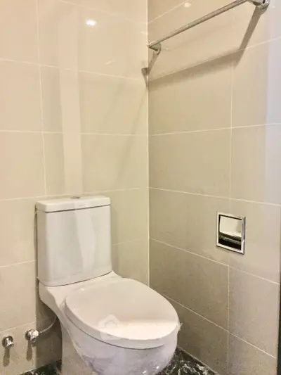 Modern bathroom with sleek toilet and towel rack in a contemporary real estate property.