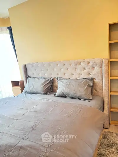Cozy bedroom with plush headboard and soft lighting, perfect for relaxation.