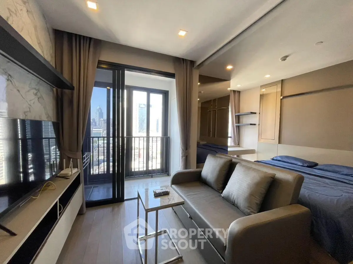 Modern studio apartment with balcony and city view, featuring sleek furniture and open layout.