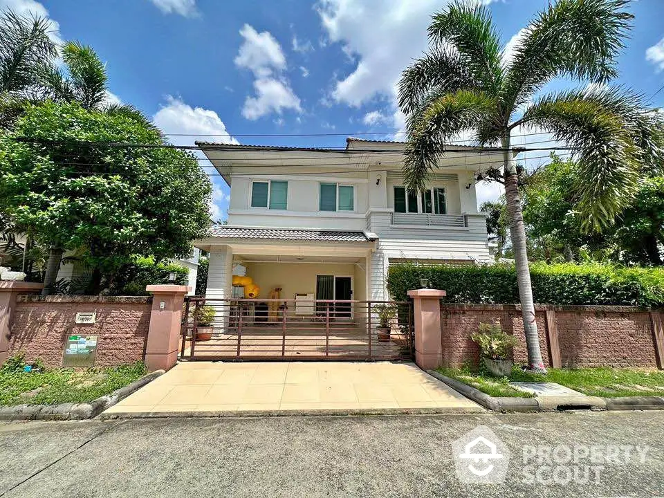 Stunning two-story house with lush garden and spacious driveway under clear blue skies.