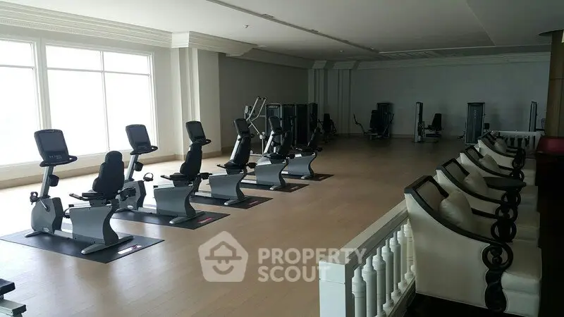 Spacious gym with modern exercise equipment and large windows for natural light.