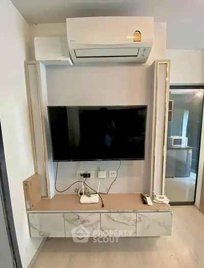 Modern living room with wall-mounted TV and air conditioning unit, sleek marble cabinet below.