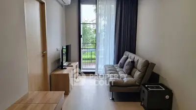 Modern living room with balcony view, featuring sleek furniture and natural light.