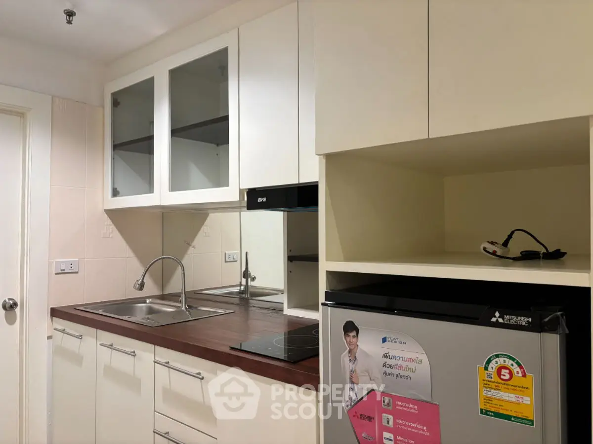 Modern kitchen with sleek cabinetry and built-in appliances, featuring a compact fridge and electric stove.