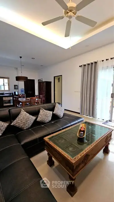 Spacious living room with elegant decor and open layout, featuring a stylish ceiling fan and large windows.