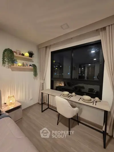 Cozy living room with dining area by the window, featuring modern decor and warm lighting.